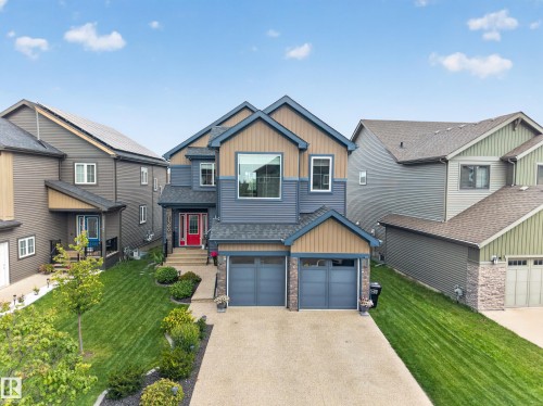 Two-story exterior with multi-toned siding, a double garage, paved driveway, and mature landscaping - 1399 Graydon Hill Way Sw, Edmonton, AB - Outdoor With Facade