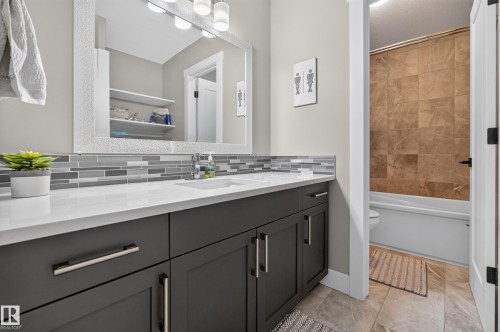 Dual vanity with a white countertop, gray shaker-style cabinetry, and mosaic tile backsplash - 1399 Graydon Hill Way Sw, Edmonton, AB - Indoor Photo Showing Bathroom