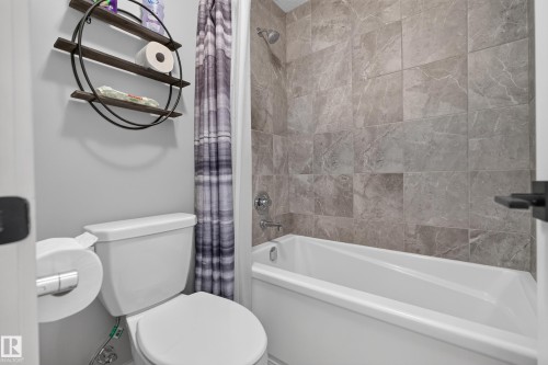 Bathtub with tiled surround, chrome shower fixtures, and white toilet - 1399 Graydon Hill Way Sw, Edmonton, AB - Indoor Photo Showing Bathroom