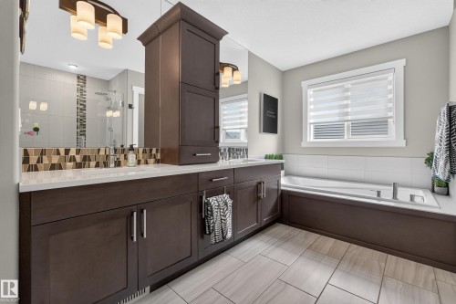 Dual vanity with dark wood-finish cabinetry, white countertops, and integrated sinks - 1399 Graydon Hill Way Sw, Edmonton, AB - Indoor Photo Showing Bathroom