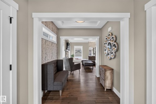 Wood-finish flooring, accent wall with a wood-look finish, white trim, and a tray ceiling - 1399 Graydon Hill Way Sw, Edmonton, AB - Indoor Photo Showing Other Room