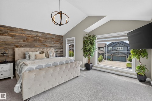 Vaulted ceiling with an orb chandelier, wood-paneled accent wall, and large picture window - 1399 Graydon Hill Way Sw, Edmonton, AB - Indoor Photo Showing Bedroom