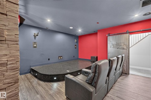 Tiered platform with integrated lighting, wood-finish flooring, accent wall with stacked stone, and barn door entry - 1399 Graydon Hill Way Sw, Edmonton, AB - Indoor