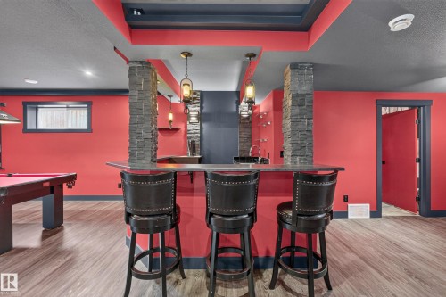 Built-in bar with stone-clad supports, wood-finish flooring, recessed lighting, and a window opening - 1399 Graydon Hill Way Sw, Edmonton, AB - Indoor Photo Showing Other Room