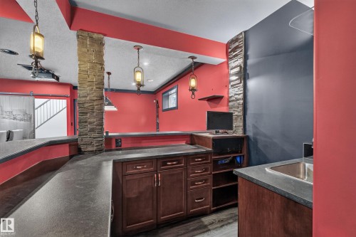 Built-in cabinetry with dark wood finish, a stainless steel sink, and stone-clad architectural columns - 1399 Graydon Hill Way Sw, Edmonton, AB - Indoor