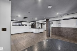 Expansive entertainment area featuring wood-finish flooring, recessed lighting, and a stone accent wall - 