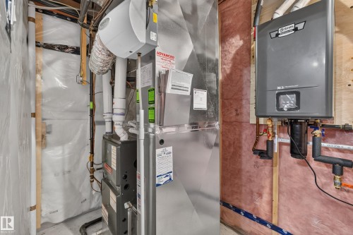 Furnace system with humidifier, exposed insulation, and wall-mounted water heater - 1399 Graydon Hill Way Sw, Edmonton, AB - Indoor Photo Showing Basement