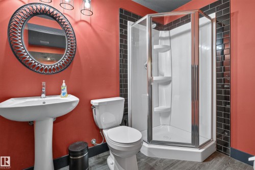 Pedestal sink, round framed mirror, corner shower enclosure, toilet, and subway tile accent - 1399 Graydon Hill Way Sw, Edmonton, AB - Indoor Photo Showing Bathroom