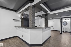 Built-in bar with a stone-clad support pillar, pendant lighting, and a dark countertop - 