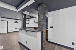 Built-in bar with stone-clad pillars, pendant lighting, and wood-finish flooring - 