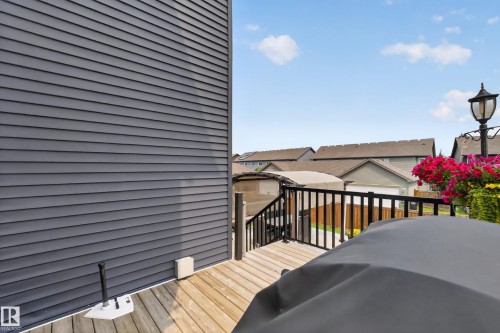 Wood-finish deck with a black railing, featuring a mounted outdoor light fixture and dark horizontal siding - 1399 Graydon Hill Way Sw, Edmonton, AB - Outdoor With Deck Patio Veranda With Exterior