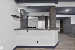 Bar area featuring a stone-clad support column, pendant lighting, stone countertop, and wood-finish flooring - 