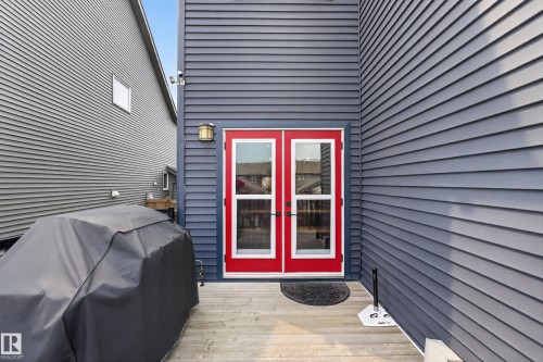 Gray siding exterior featuring red framed glass panel doors and a wood-finish deck - 1399 Graydon Hill Way Sw, Edmonton, AB - Outdoor With Exterior