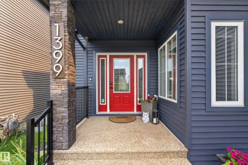 Red entry door with sidelights, complemented by a stone-clad pillar and dark siding - 1399 Graydon Hill Way Sw, Edmonton, AB - Outdoor With Exterior