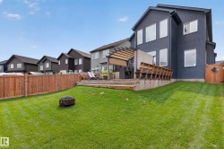 Expansive backyard featuring a tiered wood deck with pergola, wood fence, and a generous lawn - 
