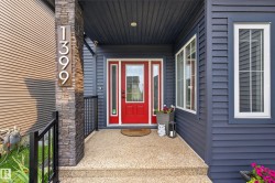 Red entry door with sidelights, complemented by a stone-clad pillar and dark siding - 