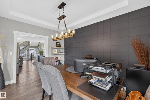 Recessed ceiling, wood-finish flooring, accent wall with geometric paneling, wood and metal chandelier, built-in shelving - 1399 Graydon Hill Way Sw, Edmonton, AB - Indoor Photo Showing Dining Room