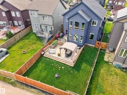 Expansive backyard featuring a manicured lawn, wood fencing, and a multi-level deck with a pergola - 