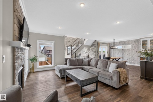 Stone-clad fireplace with a white mantel, wood-finish flooring, recessed lighting, and a stone-accented staircase - 1399 Graydon Hill Way Sw, Edmonton, AB - Indoor Photo Showing Living Room With Fireplace