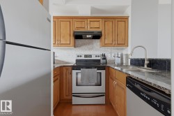 Kitchen featuring wood-finish cabinetry, stone countertops, and a tile backsplash - 
