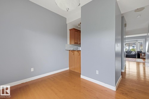 Hardwood flooring, light gray wall finishes, recessed lighting, and built-in cabinetry with a stone-finish countertop - #9 13215 153 Av Nw, Edmonton, AB - Indoor Photo Showing Other Room