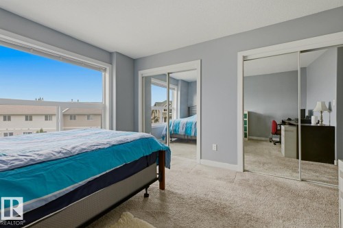 Wall-to-wall carpeting, two large windows, and two mirrored sliding closet doors - #9 13215 153 Av Nw, Edmonton, AB - Indoor Photo Showing Bedroom