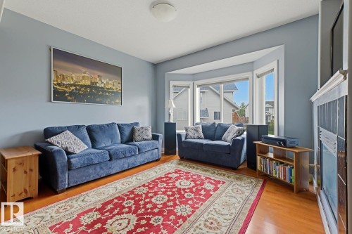 Bay window with multiple panes, light blue wall paint, wood-finish flooring, built-in shelving, and white trim - #9 13215 153 Av Nw, Edmonton, AB - Indoor Photo Showing Living Room