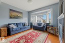 Bay window with multiple panes, light blue wall paint, wood-finish flooring, built-in shelving, and white trim - #9 13215 153 Av Nw, Edmonton, AB  - Indoor Photo Showing Living Room 