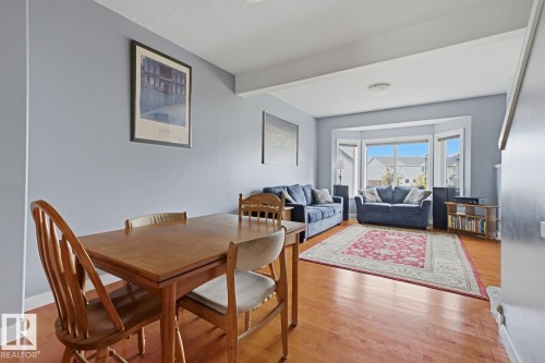Hardwood flooring throughout, neutral wall tones, and a large bay window - #9 13215 153 Av Nw, Edmonton, AB - Indoor