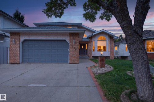 Attached two-car garage, brick facade with stucco accents, arched windows, concrete driveway, and a front walkway - 306 Twin Brooks Drive Nw, Edmonton, AB 