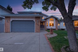 Attached two-car garage, brick facade with stucco accents, arched windows, concrete driveway, and a front walkway - 