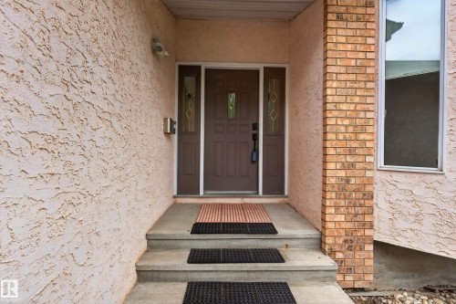 Textured exterior finish with brick accent column, main entry door with decorative glass sidelights, and concrete steps - 306 Twin Brooks Drive Nw, Edmonton, AB 