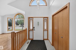 Vaulted ceiling with an arched transom window, wood-finish flooring, and white interior doors - 