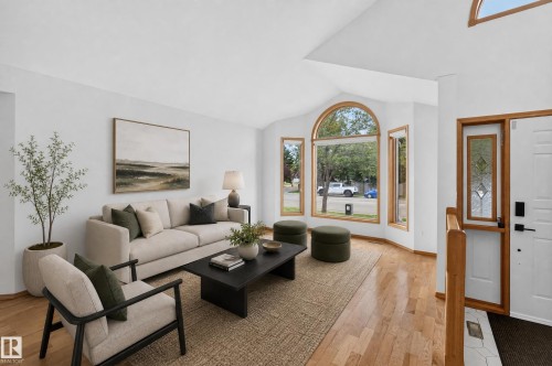 Bright living area featuring wood-finish flooring, a vaulted ceiling, and an arched picture window - 306 Twin Brooks Drive Nw, Edmonton, AB 