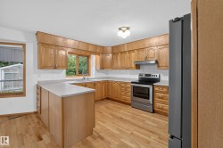 Kitchen featuring wood cabinetry, light-toned countertops, stainless steel appliances, and wood-finish flooring - 