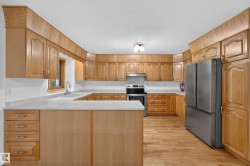 U-shaped kitchen with wood-finish cabinetry, white countertops, and stainless steel appliances - 