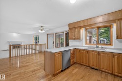 Hardwood flooring, wood cabinetry, white countertops, built-in dishwasher, and a fireplace - 