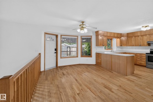 Wood-finish flooring throughout, kitchen with light wood cabinetry and light countertops, stainless steel range, and a ceiling fan with light fixture - 306 Twin Brooks Drive Nw, Edmonton, AB 