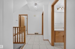 Tiled flooring, wood-finish trim and doors, wood-finish stair railing, recessed ceiling light fixture, and vanity with integrated sink - 