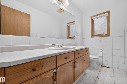 Full-length vanity with dual sinks, warm wood-finish cabinetry, and a light-toned countertop - 306 Twin Brooks Drive Nw, Edmonton, AB 