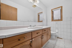 Full-length vanity with dual sinks, warm wood-finish cabinetry, and a light-toned countertop - 
