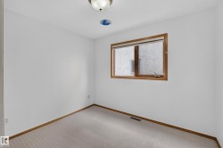 Recessed window with wood-finish trim, neutral wall color, and carpeted flooring - 