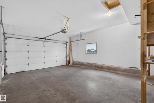 Concrete flooring garage featuring a white overhead door, an automatic garage door opener, and a single window - 306 Twin Brooks Drive Nw, Edmonton, AB 