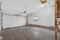 Concrete flooring garage featuring a white overhead door, an automatic garage door opener, and a single window - 