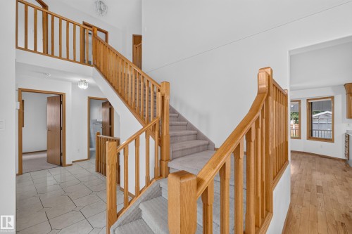 Multi-level staircase with wood railings, carpeted treads, and an upper landing with matching wood railings - 306 Twin Brooks Drive Nw, Edmonton, AB 