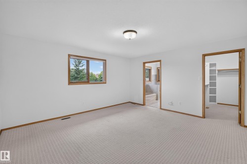 Carpeted room with a window, ceiling-mounted light fixture, and two wood-trimmed doorways - 306 Twin Brooks Drive Nw, Edmonton, AB 