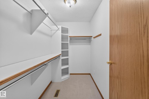 White custom shelving system with multiple storage rods, built-in corner shelving, and a brass-finished door handle - 306 Twin Brooks Drive Nw, Edmonton, AB 