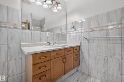 Bathroom featuring a wood-finish vanity with a built-in sink, a light-toned countertop, and a large wall-mounted mirror - 