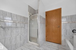 Tiled shower with glass enclosure, wood-finish door, and integrated bathtub - 
