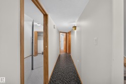 Hallway featuring patterned resilient flooring, light-toned wall paint, decorative wall sconces, and wood-finish door frames - 